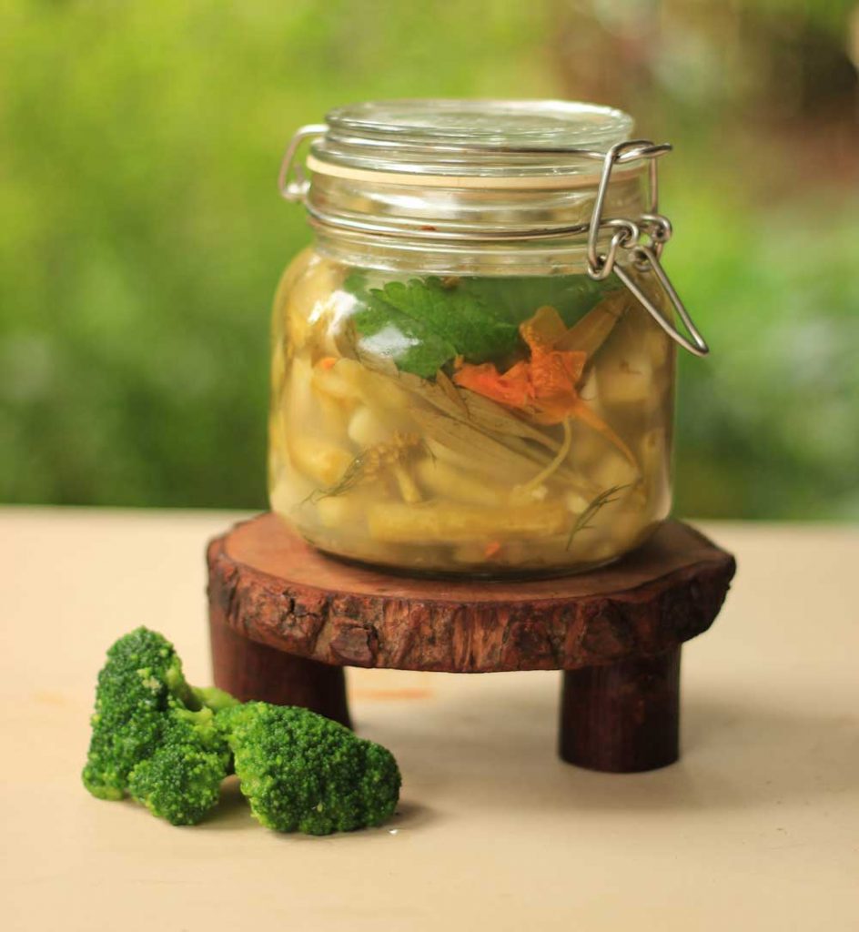 A jar of fermented broccoli stems and nasturtium flowers and leaves 