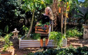 lady in garden with a box of fresh organic produce