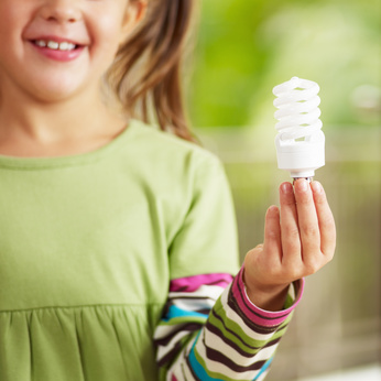 Girl holding light bulb and smiling. Selective focus