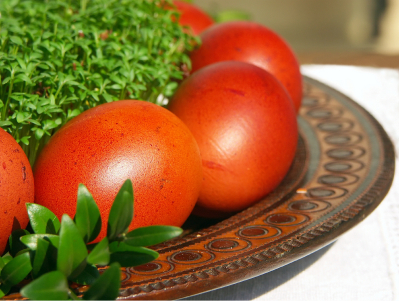Easter eggs dyed with onion leaf extract arranged on wooden plate with cress